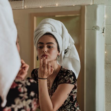 woman putting makeup in front of mirror